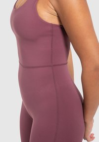 Bordeauxkleurig sportieve bodysuit met een aansluitend ontwerp, zachte textuur en contrasterende stiksels, die een slanker silhouet accentueert.