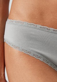 Grauer Stoffslip mit einem zarten Spitzensaum am Bund, glatter Textur und schlichtem, tailliertem Design.