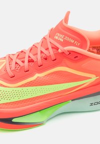 Nike Zoom Fly Laufschuh in leuchtendem Koralle mit gelben Akzenten. Verfügt über ein Obermaterial aus Mesh, eine aerodynamische Form und eine leichte grüne Sohle.