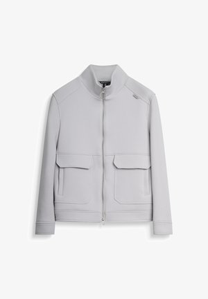 Lichtgrijze zip-up jas, gekenmerkt door een hoge kraag, twee voorzakken en subtiele stiksels. Gemaakt van textiel met een structuur.