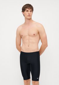 Čierne plavky so priliehavým strihom, vyrobené z hladkého materiálu, s malým bielym logom Nike na ľavom stehne.