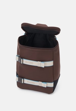 Sac à dos rectangulaire marron avec fermeture éclair supérieure ouverte, deux bretelles beiges réglables avec des bords bleus et un marquage "RAINS" à l'avant.