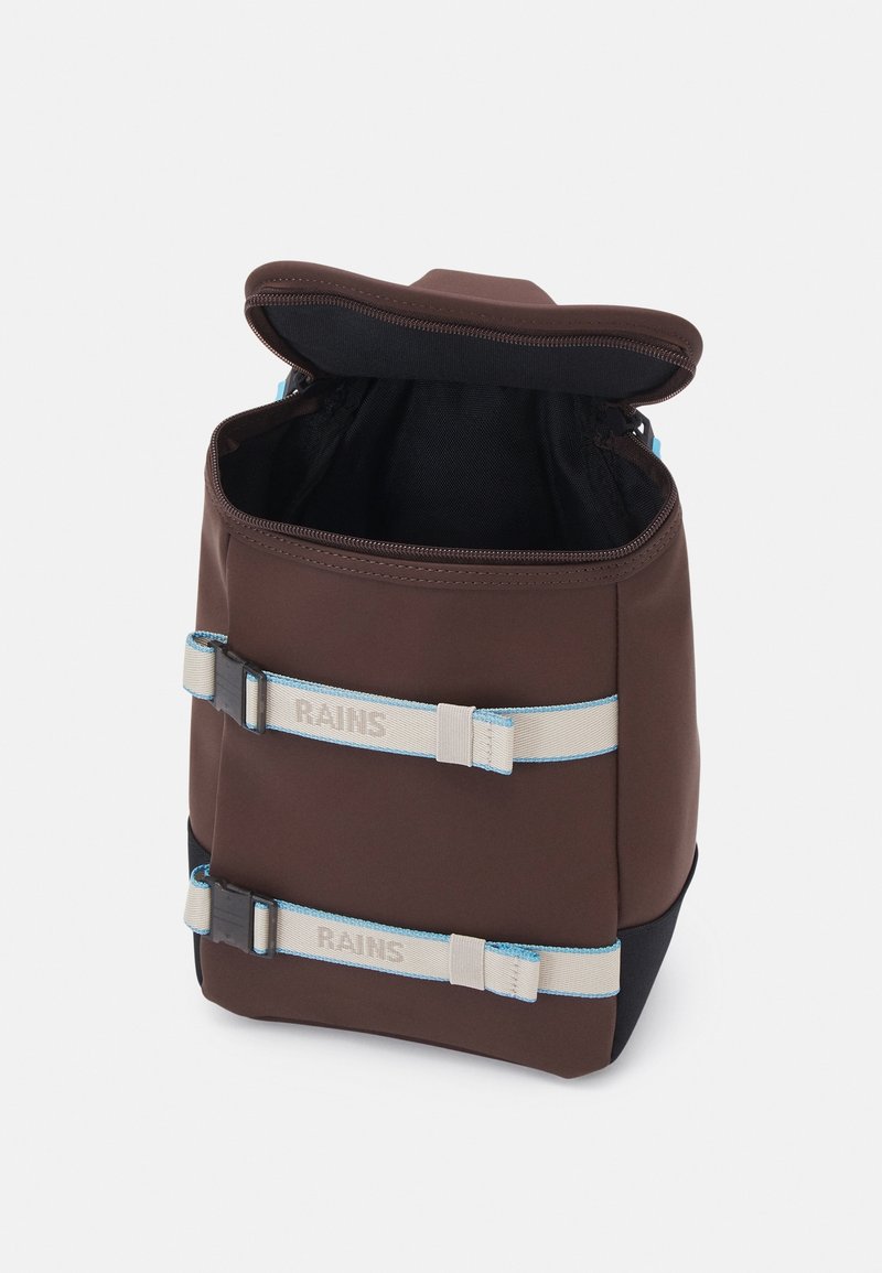 Sac à dos rectangulaire marron avec fermeture éclair supérieure ouverte, deux bretelles beiges réglables avec des bords bleus et un marquage "RAINS" à l'avant.