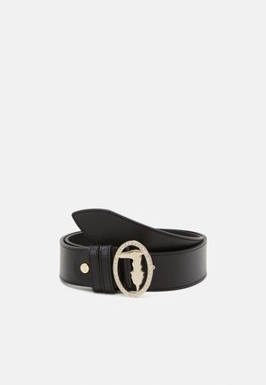 Ceinture en cuir noir avec une boucle ovale dorée décorée de petits cristaux et une découpe en silhouette au centre.