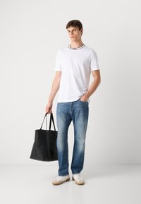 Hvid kortærmet t-shirt med detalje i sort ved kraven, blå denim jeans og en sort læder tote bag, parret med hvide sneakers.