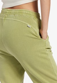 Lys grønne sweatpants lavet af blød bomuld med elastisk talje, sidelommer og et lille logo-tag på baglommen.
