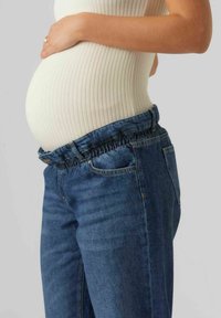 Graviditetsjeans med elastisk midjeband, blå denim, framfickor och en tight passform runt höfterna för att rymma en gravidmage.