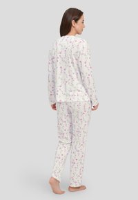 Conjunto de pijama floral en un tejido suave y ligero. Base blanca con un patrón floral en rosa, parte superior de manga larga y pantalones rectos.