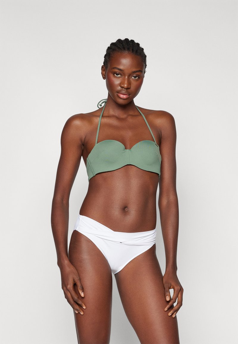 Grønn bikinitopp med sweetheart hals og halterknuter, parret med hvite høyhussein bikiniunderdeler. Glatt stoff, minimalistisk design.