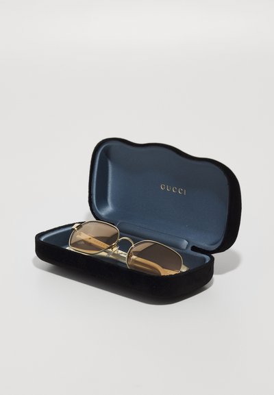 Gucci prillid mustas sametist karbis sinise siseküljega. Prillidel on kuldne raam ja pruunid toonitud läätsed.