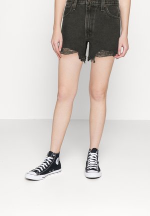 Shorts in denim nero con orli sfrangiati, design a vita alta e due tasche frontali, abbinati a sneaker alte nere.