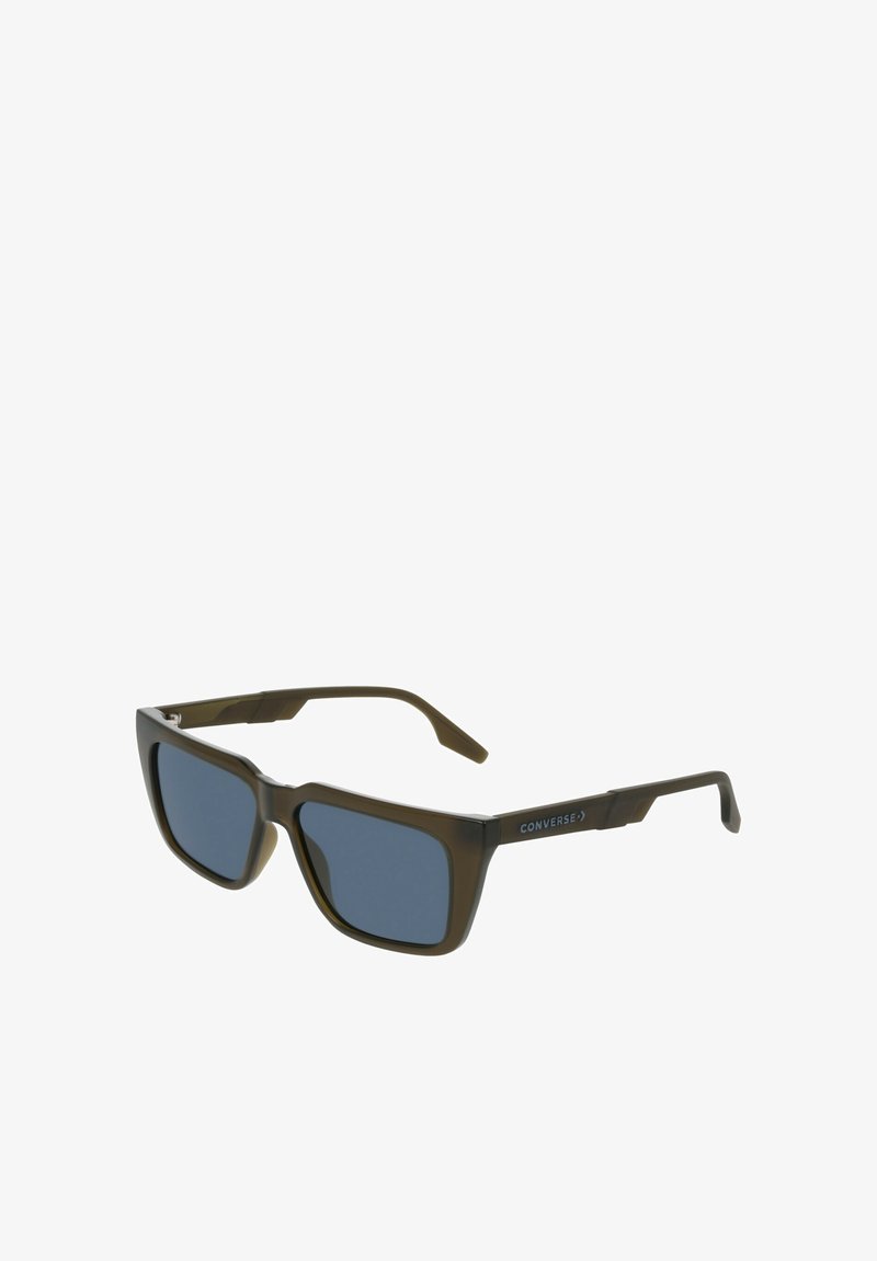 Lunettes de soleil en plastique marron avec des verres carrés, teinte bleu foncé, et accents métalliques. Logo "Converse" sur la branche. Design élégant avec des branches robustes.