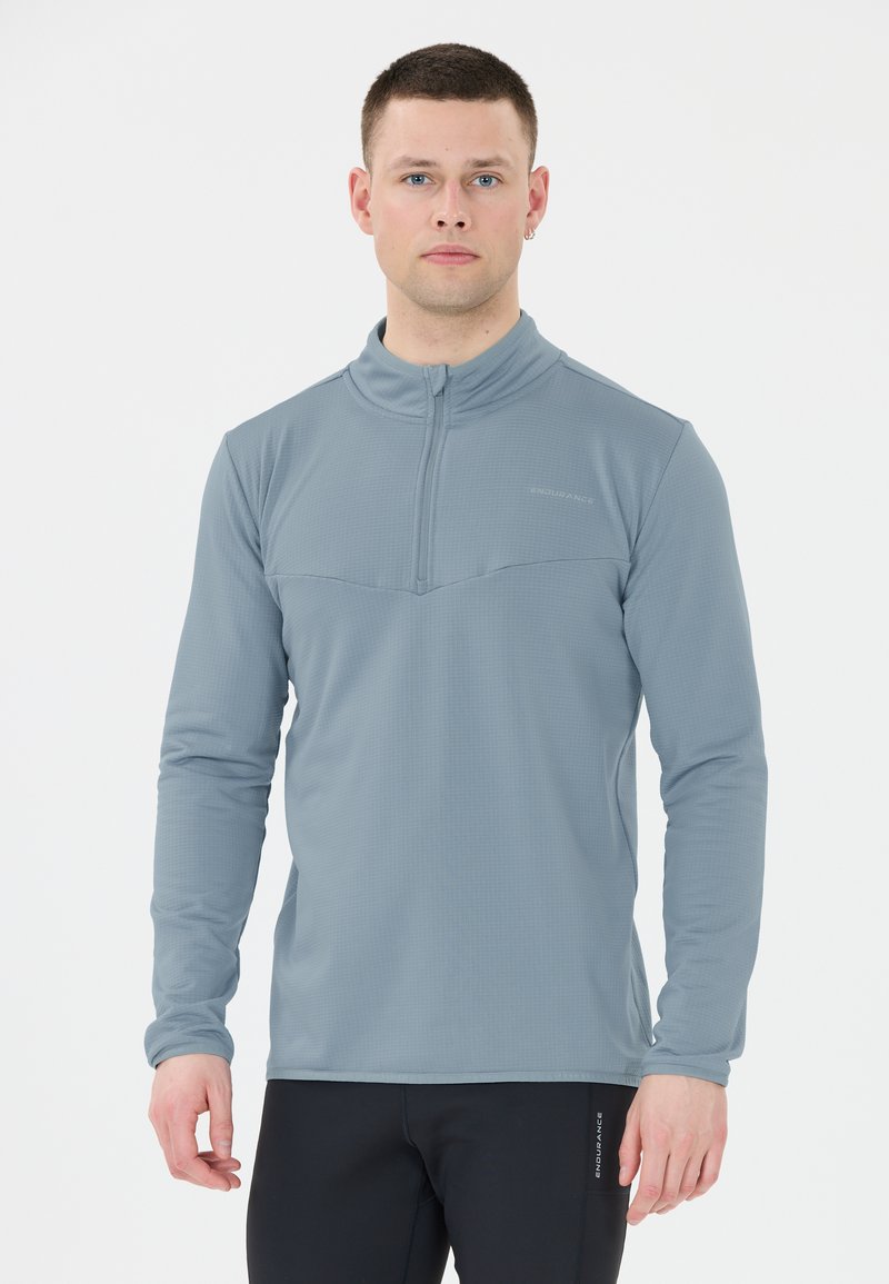 Ljusgrå långärmad träningströja med kvart-zip krage, texturerad väv och platta sömmar, uppvisad mot en enkel bakgrund.