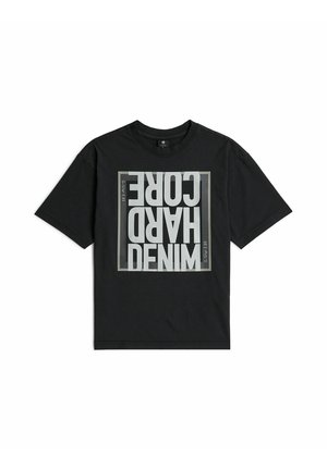 Schwarzes kurzärmeliges T-Shirt mit einem quadratischen Motiv auf der Vorderseite, das auf dem Kopf stehenden weißen Text mit der Aufschrift "DENIM HARD CORE" und kleinen Seitentext "G-Star E 89" zeigt.