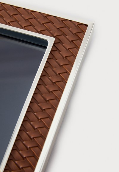 Brązowa skórzana ramka na zdjęcia o plecionej fakturze i metalicznym srebrnym brzegu, prezentująca błyszcz�ący czarny wkład do ekspozycji zdjęć.