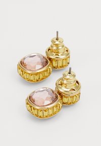 Boucles d'oreilles dorées avec des pierres en acrylique rose facettées, montées sur des bases texturées et striées, avec fermetures à tige.