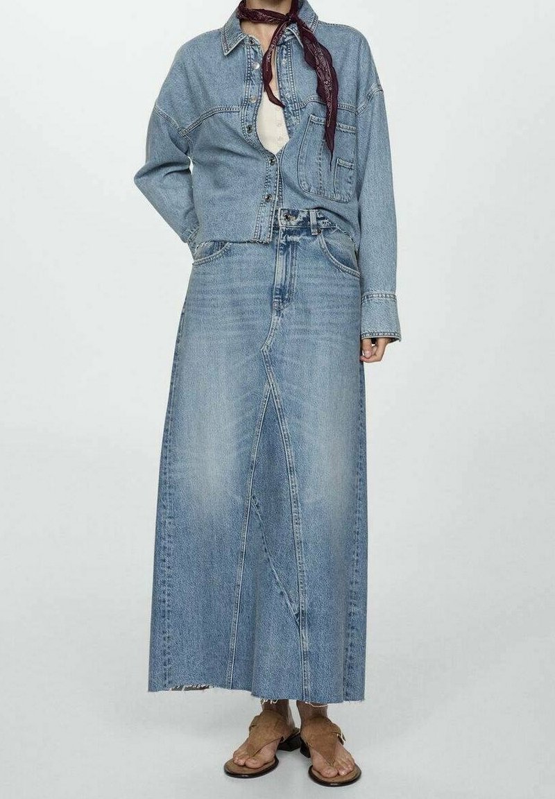 Jeansjacke und Maxiröcke-Set in Hellblau. Die Jacke hat Fronttaschen und einen Knopfverschluss. Der Rock hat einen vorderen Schlitz und einen fransigen Saum.