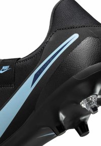 Black soccer cleat with a textured upper, featuring a light blue stripe and transparent studs on the sole for traction and support.