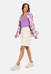Lyse lilla ternet skjorte over en lilla tanktop, creme farvede plissee shorts og beige sneakers; glatte stofteksturer med kontrasterende farver.