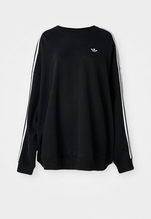 Sweatshirt noir oversized en tissu doux, avec des rayures blanches le long des manches et un petit logo sur la poitrine. Encolure ronde.