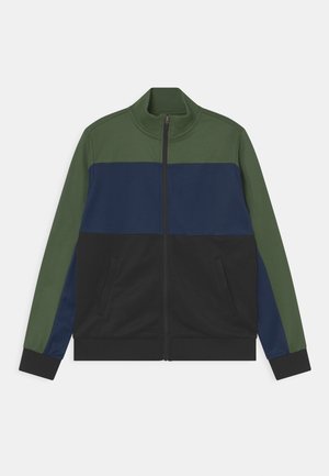 Veste de survêtement pour homme à blocs de couleur avec épaules et manches vertes, poitrine bleu marine, partie inférieure noire, fermeture éclair intégrale à l'avant, et poches latérales.
