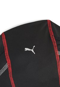 Top sportivo nero con cuciture rosse, caratterizzato da un logo Puma argento sul davanti. Il tessuto sembra liscio ed elastico.