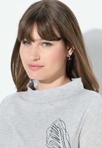 Grauer Sweatshirt mit hohem Kragen, ausgestattet mit einem schwarzen Blattumriss-Design. Weicher Stoff, lockere Passform und minimalistischer Stil.