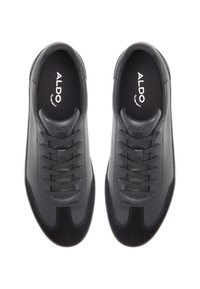 Zapatillas de cuero negro con textura suave, cierre de cordones, punta redondeada y suela de goma blanca. Marca visible en las plantillas.