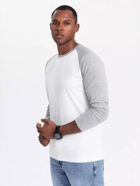 Weißes Langarmshirt mit grauen Raglanärmeln, kombiniert mit hellblauen Jeans. Das Modell trägt eine schwarze Uhr an einem Handgelenk.