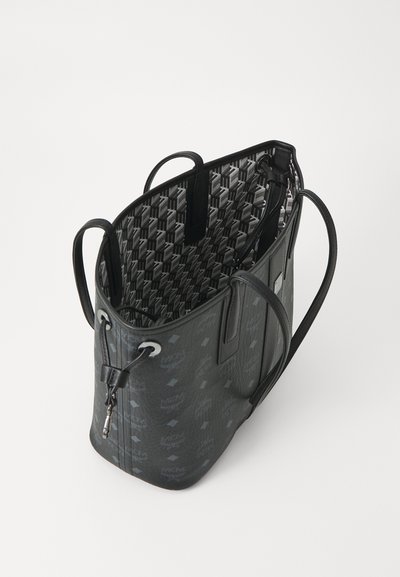 Borsa a tote in pelle nera con loghi MCM grigi, doppi manici e fodera interna a motivo che presenta un design MCM ripetuto.