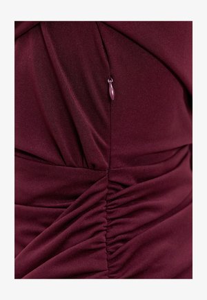 Robe bordeaux avec texture froncée, dotée d'une fermeture éclair latérale et d'un tissu doux et extensible. Design élégant et cintré.