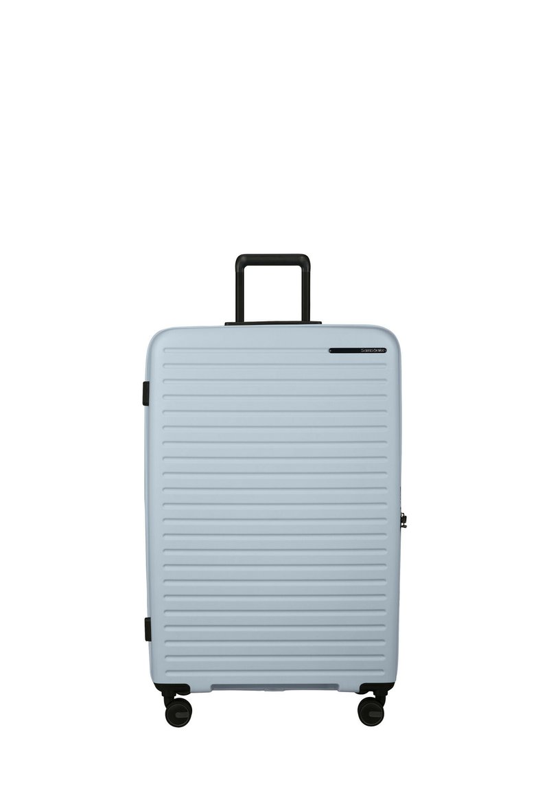 Hard-shell suitcase in light blue, featuring horizontal ribbed design, black wheels, and a retractable handle. Minimal branding detail.
