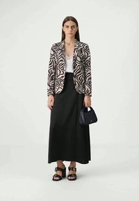 Zebra-patterned blazer in beige and black, white top, black maxi skirt, black handbag, and black sandals with buckles.