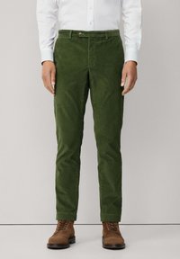 Groene corduroy broek met een slim fit, voorzien van een knoopsluiting, riemlussen en een gestructureerde stof. Draagt bij bruin veterschoenen.