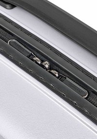 Nahaufnahme eines schwarzen Reißverschlusses mit silbernen Zippern, die mit "packtastic" beschriftet sind, auf einem weißen strukturierten Koffer.