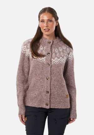 Donna che indossa un cardigan malva con bottoni e motivi geometrici bianchi sul petto e sulle spalle, abbinato a pantaloni neri.