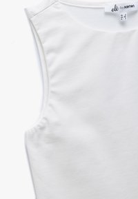 Hvid ærmeløs tanktop med rund hals og synlig "olé by Koton" tøjmærke indeni halsudskæringen.