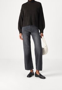 Tumma neuletasku, korkea vyötäröinen harmaa farkut, mustat loafersit ja valkoinen käsilaukku, joissa on rento istuvuus ja suora lahkeensuunnittelu.