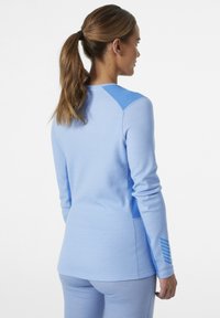 Top atlético de manga larga azul claro con parches texturizados en los hombros y detalles a rayas en las mangas. Tejido suave con un diseño ajustado.