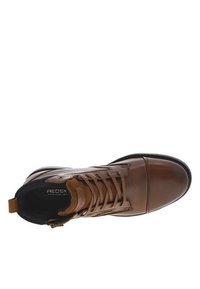 Botín de cuero marrón hasta el tobillo con un acabado suave, puntera redonda, diseño de cordones redondeado y un cuello de tela negra en contraste.
