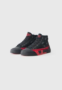 Zwarte hoge sneakers met rode accenten en versleten stof. Heeft een vetersluitingen en een rubberen zool met een gestructureerde afwerking.