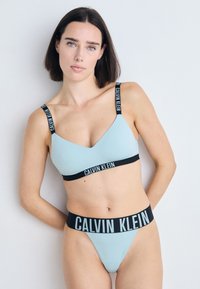 Lichtblauw naadloze bh met zwarte "CALVIN KLEIN" logo schouderbanden en bijpassende bikinibroek, voorzien van elastische banden en een minimalistisch ontwerp.