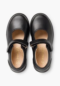 Los zapatos Mary Jane de cuero negro presentan una punta redonda, bordes con corte en ondas, una correa ajustable y un interior beige con perforaciones.