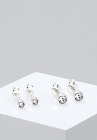 Pendientes de plata con brillantes redondos y claros al final de postes cilíndricos, sobre un fondo neutro.