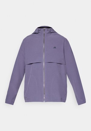 Lilla hettejakke med glidelås foran, med en klaft brystlomme, elastiske mansjetter og sømdetaljer. Adidas-logo på venstre bryst.