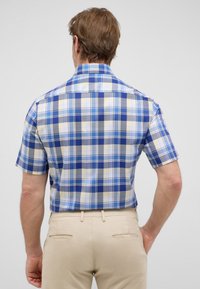 Lichtgekleurde korte mouwen geblokte shirt met blauw, grijs en geel. Button-down kraag en een relaxte pasvorm. Gecombineerd met lichtbeige broek.