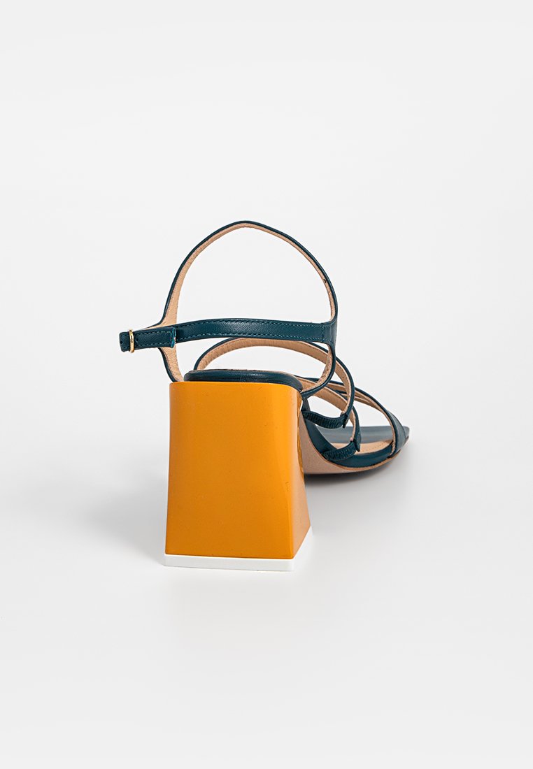 Sandale strappy teal avec un talon carré orange et une base blanche. Présente un design à bout ouvert et une fine bride de cheville réglable.