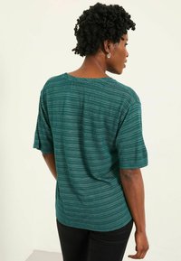Teal striped short-sleeve top made of a lightweight fabric, featuring a loose fit and a soft texture. Back view shows a round neckline.