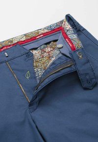 Marineblauwe broek met een rits- en knoopsluiting; de binnenkant heeft een patroonvoering in goud, rood en blauw met een geborduurd looflogo.