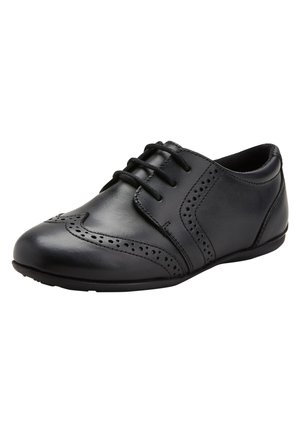 Schwarze Lederschuhe mit runder Zehenpartie, die dekorative Perforationen und überlappende Designelemente aufweisen. Mit flachen Schnürsenkeln und Schnürverschluss.